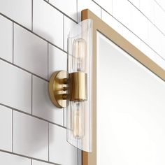 a bathroom mirror mounted to the side of a white tiled wall next to a gold framed medicine cabinet