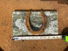 an old rusty horseshoe sitting on top of a piece of wood next to a measuring tape