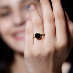 a close up of a person holding a ring in their hand with a black stone on it