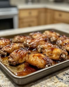 some chicken wings are sitting on a baking pan