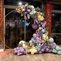 a large balloon arch decorated with flowers and balloons