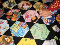 a child's hand is on the top of a quilt that has many different designs