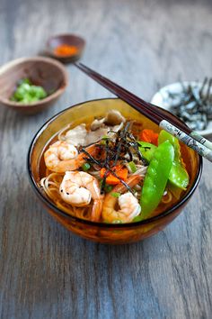 a bowl filled with shrimp and vegetables next to chopsticks