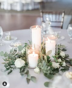 candles and greenery on a white table cloth