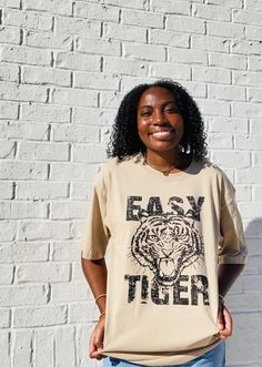 Stay on-trend with the Easy Tiger Oversized Graphic Tee. This tan-colored shirt is designed with a slightly oversized fit, providing both comfort and style. Perfect for any casual occasion, this tee is a must-have for any fashion-forward individual. Trendy Khaki Crew Neck T-shirt, Trendy Brown Relaxed Fit T-shirt, Spring Oversized Beige T-shirt, Trendy Beige Relaxed Fit T-shirt, Oversized Brown T-shirt For Fall, Trendy Beige T-shirt For Streetwear, Trendy Beige Streetwear T-shirt, Trendy Fall T-shirt For Day Out, Beige Cotton T-shirt For Day Out