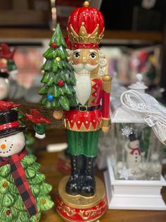 a nutcracker figurine next to a christmas tree and other ornaments on a table