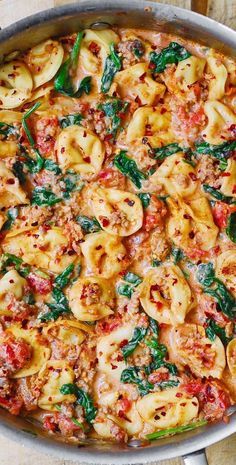 a pan filled with pasta and spinach covered in sauce