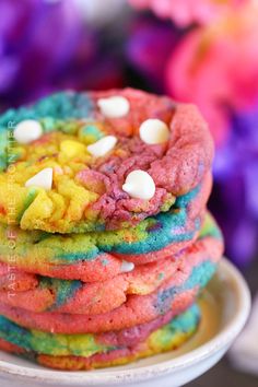 a stack of colorful cookies sitting on top of a white plate with marshmallows