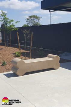 a concrete bench sitting on top of a cement slab in front of a black fence