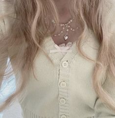 a woman with long blonde hair wearing a white sweater