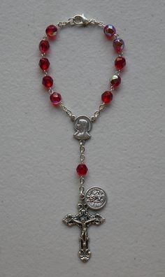 "Precision molded red beads with silver tone metal chain and clasp. SIZE/LENGTH: Total length is 6.75\" including the silver tone Fleur de Lis Crucifix. BEADS: Quality 6 mm beads carefully assembled on a silver tone chain. MEDAL: Saint Christopher Made in Italy Center piece has The Sacred Heart of Jesus and The Immaculate Heart of Mary on the back. The Saint Christopher medal is shown on picture. A Timeless Gift ~ Perfect for any person! This is a very good quality and elegant rosary for use as Red Adjustable Rosary With Round Beads, Adjustable Red Rosary With Round Beads, Adjustable Red Rosary, Adjustable Red Beaded Rosary, Red Rosary Beads For Jewelry Making, Red Beaded Rosary With Round Beads, Adjustable Silver Rosary With Faceted Beads, Silver Rosary With Faceted Beads, Silver Rosary With Faceted Round Beads