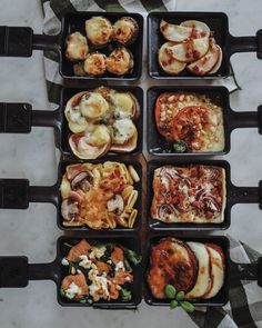 six square trays filled with different types of food on top of a marble table