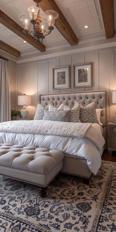 a large white bed sitting under a chandelier in a bedroom next to a window