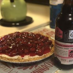 a bottle of beer next to a pie on a table