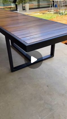 a wooden table sitting on top of a cement floor next to a potted plant