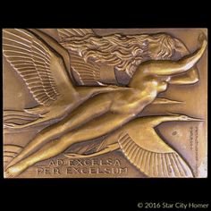 a bronze plaque with an image of a naked woman on it's side and the words, ad excelsia per exegesumum