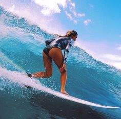 a woman riding a wave on top of a surfboard