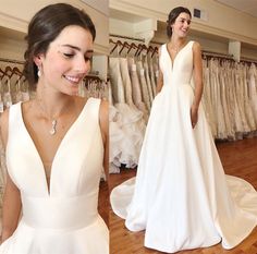 a woman standing in front of a rack of wedding gowns and looking at the camera