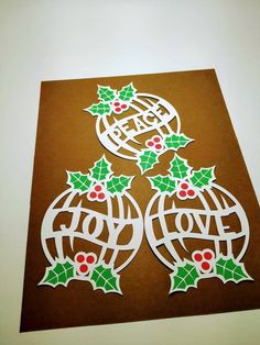 two christmas ornaments with holly leaves and the word hope on them are cut out from brown paper