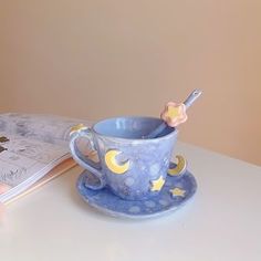 a cup and saucer sitting on top of a table next to an open book