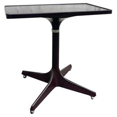 a black table with a glass top and wheels on the bottom, against a white background