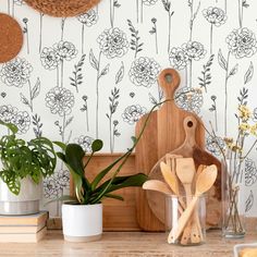 kitchen utensils and cutting board on counter with wallpaper