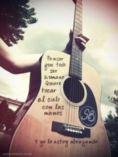 a person holding a guitar with spanish writing on it