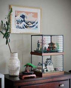 a vase with some plants on top of it next to a shelf filled with legos