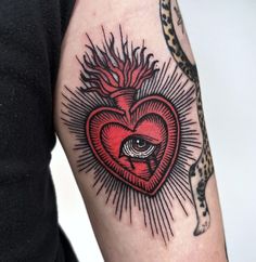 a person with a heart tattoo on their arm and an eye in the middle of it