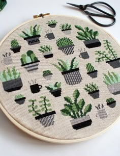 a cross stitch pattern with potted plants on it and some scissors next to it