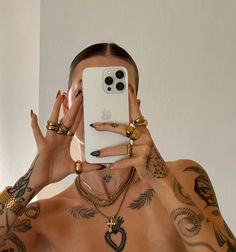 a man with tattoos holding up his phone to take a selfie in the mirror