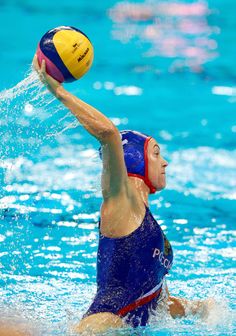 a woman is playing water polo in the pool while splashing it with her hands