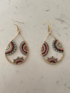 two pairs of earrings with beaded details on top of a marble countertop,