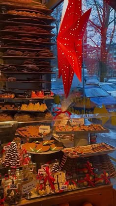 a display case filled with lots of different types of desserts and pastries in front of a window