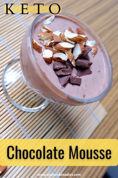 a glass filled with chocolate and almonds on top of a wooden table next to a spoon