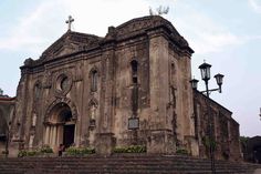 an old church with steps leading up to it and a cross on the top tower