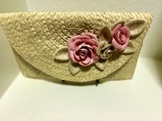 a straw purse with pink flowers on the front and side, sitting on a white surface