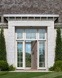 the front door to a house with two windows and an entry way leading into it