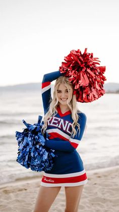 a beautiful young woman standing on top of a beach holding a cheerleader pom - pom