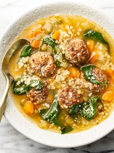 a white bowl filled with soup and meatballs on top of couscouse