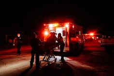 some people standing in front of an ambulance at night