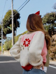 a woman walking down the street with her back to the camera, wearing a sweater and jeans