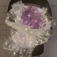 a person holding a bouquet with lights on it in their hands and wrapped in plastic