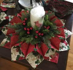 a christmas centerpiece on a table with candles and napkins