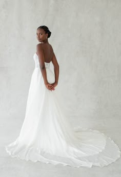 a woman in a white wedding dress posing for the camera with her hands on her hips