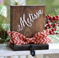 a wooden block with the word mellisa on it sitting next to some pine branches