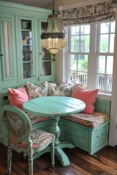 a table and chairs in a room with green walls, windows and wood flooring