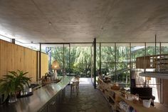 a long table in the middle of a room with lots of windows and plants on it