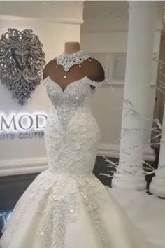 a white wedding dress on display in front of a wall with the word modd