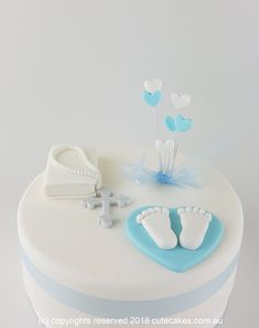 a white cake with blue decorations and baby's feet